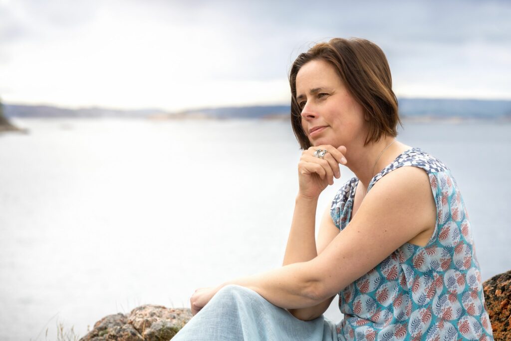 Photo of Marion Miller sat contemplating by the ocean.